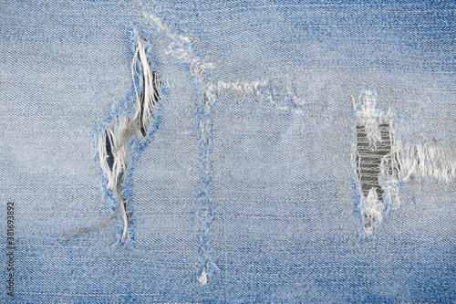 Patch tear Denim jeans textile texture surface for background or wallpaper with copy space. Close up of torn blue jeans fabric pattern design.