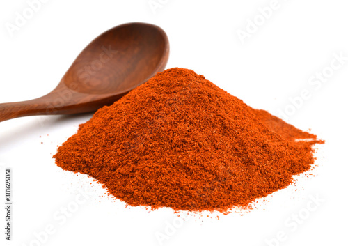 Powdered red pepper pile from top and wooden spoon on white background