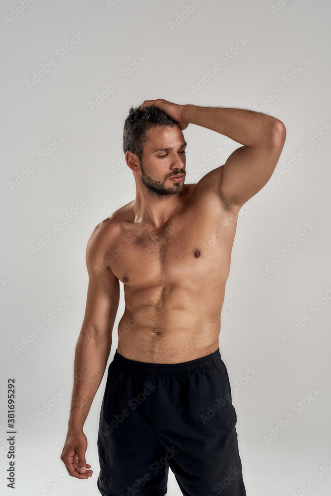 Perfect body. Young muscular caucasian man showing his naked torso while posing shirtless isolated over grey background