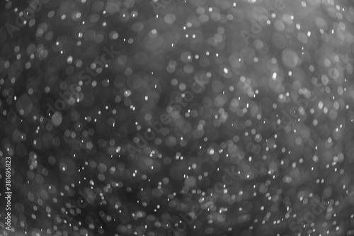 snow or rain bokeh texture overlay on black background. © iloli