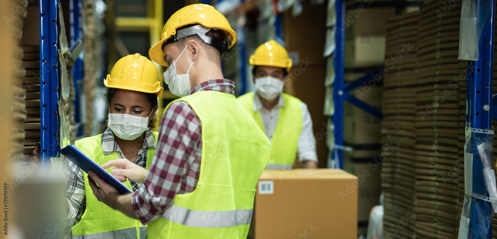 Diverse group of warehouse workers wear protective face mask to prevent COVID-19 infection working and doing inventory in storehouse together. warehouse and inventory concept. Diverse group of warehouse workers wear protective face mask to prevent COVID-19 infection working and doing inventory in storehouse together. warehouse and inventory concept.