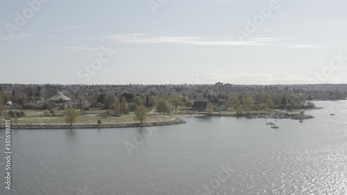 Slow aerial pan in.  Over water, to marina, beach, park. Urban neighborhood. Kitsilano, Maritime museum,Vanier Park,  Vancouver BC Canada. photo