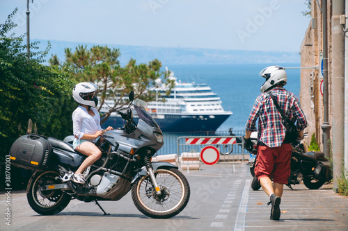 Man and woman. Love and relationships. Tourism and travel. Motorcycle for tours around the world. Street of sunny Italy. Ocean liner at sea in the background. Sorrento