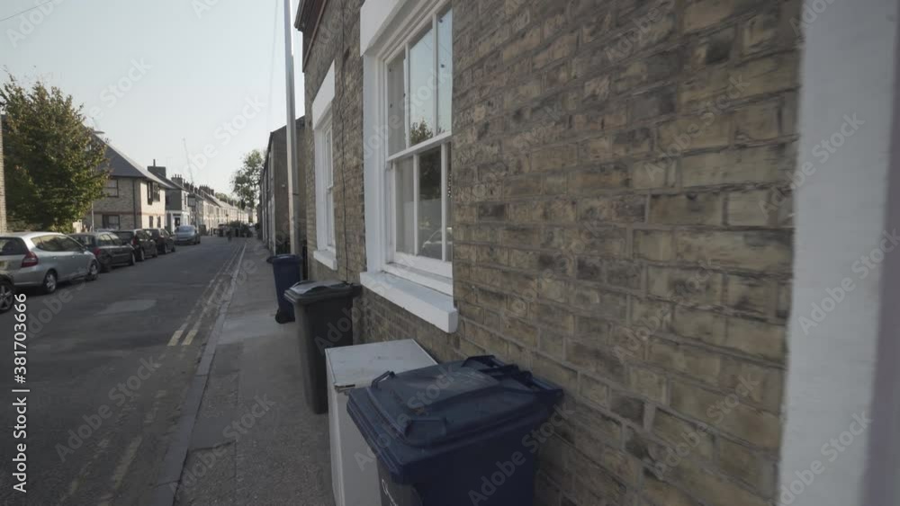 Steady wide angle shot of typical street in cambridge city england uk. Beautiful house entrance with red door and white frame. Recycle bins on the sidewalk Steady wide angle shot of typical street in cambridge city england uk. Beautiful house entrance with red door and white frame. Recycle bins on the sidewalk