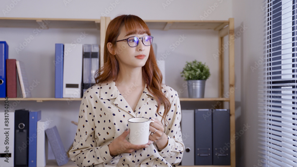 portrait happy asian woman ceo is enjoy having morning tea near window, looking into distance with a smile. portrait happy asian woman ceo is enjoy having morning tea near window, looking into distance with a smile.