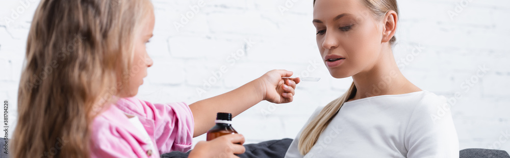 Website header of sick woman sitting near child with spoon and syrup Website header of sick woman sitting near child with spoon and syrup