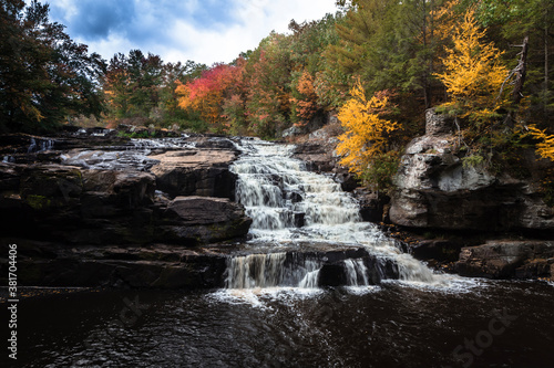 Fototapeta Naklejka Na Ścianę i Meble -  Brilliant fall foliage surrounds the beautiful cascading Shohola Falls in the Pennsylvania Poconos