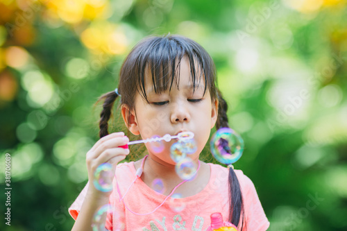 Cute kid blowing bubbles soap in the garden. Concept of digital free or unplugged outdoors activity for children.