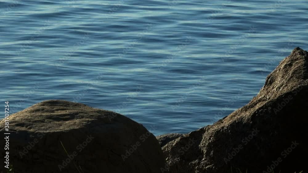 Large rocks at lake edge and rippling water beyond. Large rocks at lake edge and rippling water beyond.