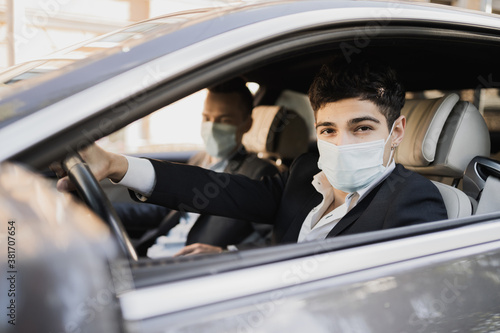 businessmen and coronavirus, pandemic, epidemic, infection. Sitting in the car wearing protective masks from covid 19, talking about work, strict business suits © muse studio