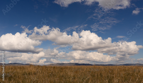 Big white clouds above the steppe meadow in Khakassia. Landscape with a grass  hills and the sky.