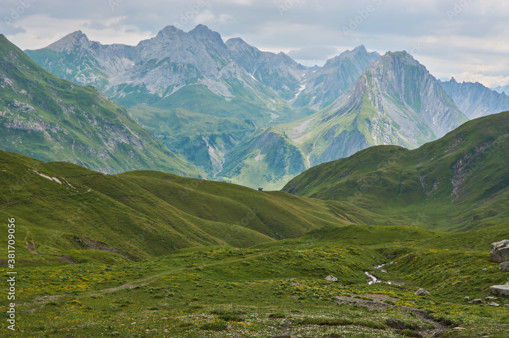 Beautiful lonely mountain landscape in the alps. Panoramic mountain landscape in the alps with green meadows and high mountains in the distance. Remote place in the mountains.