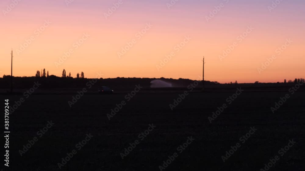 car driving past at sunset in very soft orange low light twilight car driving past at sunset in very soft orange low light twilight