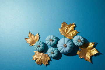 Flat lay autumn composition. Frame made of aqua colour pumpkins and dried golden leaves. Harvest thanksgiving halloween