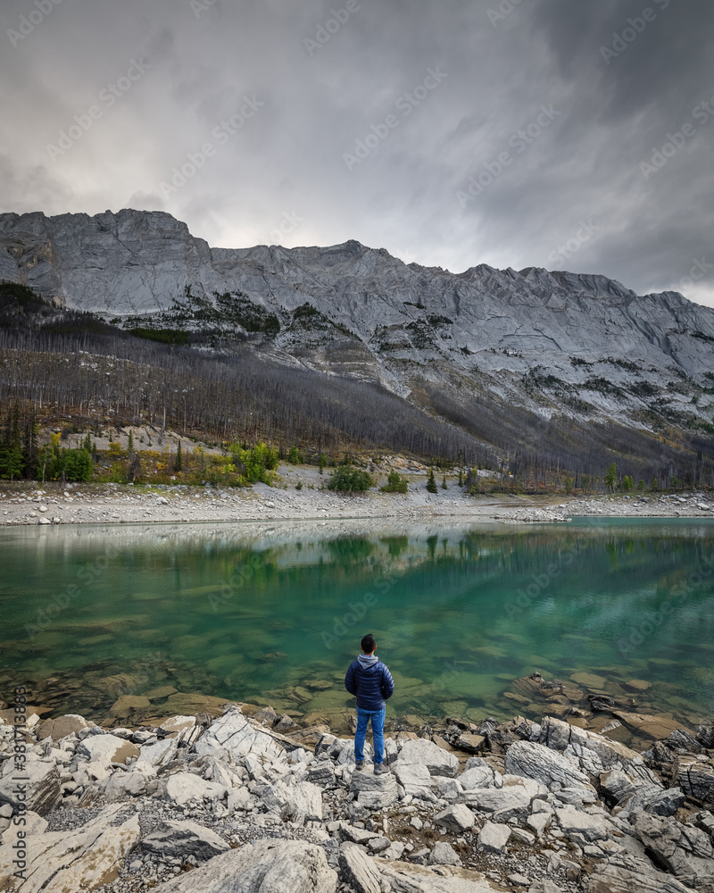 A man stands over the rocks loking at the mountains on the shore of Medicine Lake (Jasper, Alberta, Canada) A man stands over the rocks loking at the mountains on the shore of Medicine Lake (Jasper, Alberta, Canada)