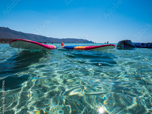 Surf Board and Kajak at crystal clear water with blue sky background