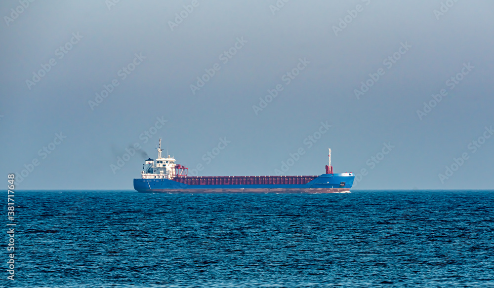 Blue cargo ship sailing on the ocean at a distance. Blue cargo ship sailing on the ocean at a distance.