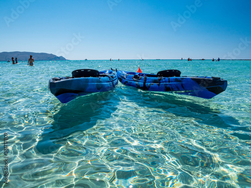 Surf Board and Kajak at crystal clear water with blue sky background