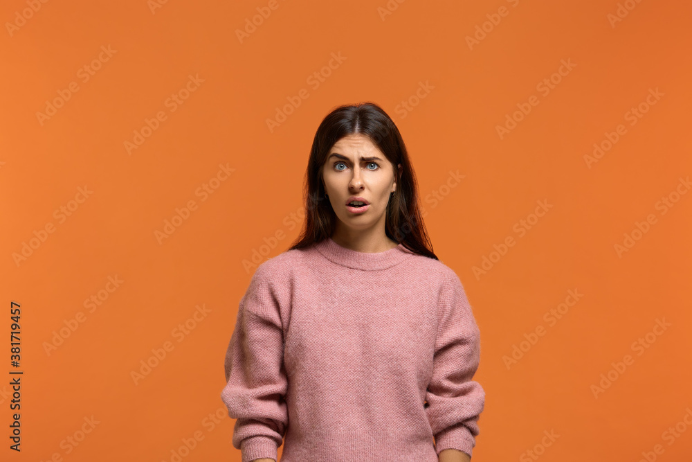 Are you serious. Portrait of shocked stunned beautiful woman in pink sweater, looking dissatisfied and surprised. On orange background Are you serious. Portrait of shocked stunned beautiful woman in pink sweater, looking dissatisfied and surprised. On orange background