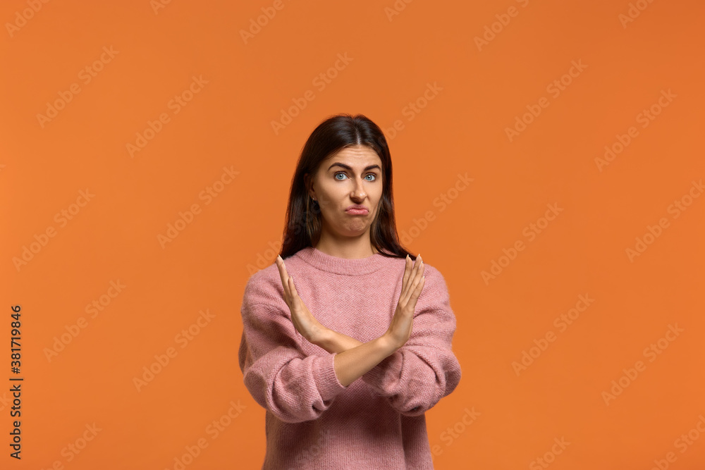 Obraz premium Ugh i won't it. Portrait of serious woman in pink sweater, makes denial hand gesture, keeps arms crossed over chest, demonstrates stop sign, says no to something or somebody. on orange background