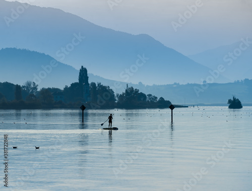 Standup Paddleboarding early in the morning on ithe dyllic shores of the Upper Zurich Lake (Obersee) between Hurden (Schwyz) and Rapperswil (St. Gallen), Switzerland
