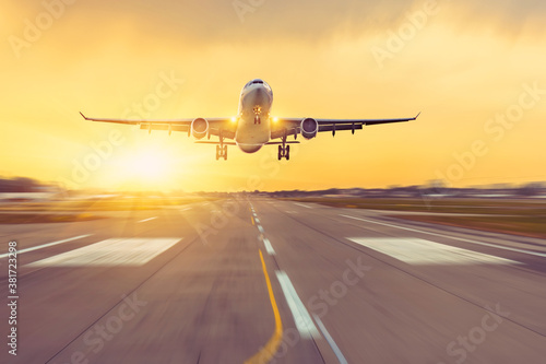 Canvas Print Airplane landing on runway speed, sunset on background.