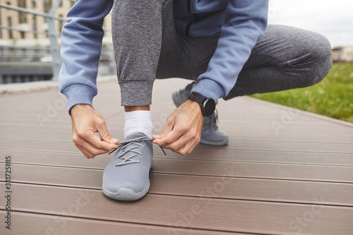 Close-up of athlete tying his sneakers before jogging outdoors