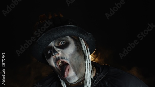 Sinister, crazy man with skeleton makeup. Guy making angry faces, shaking head, showing tongue