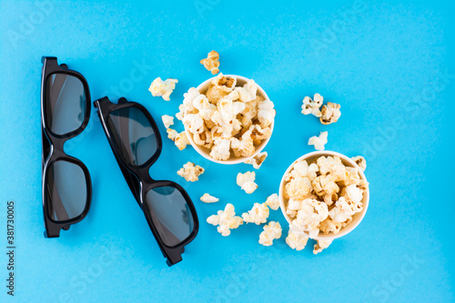 Sweet fast food. Caramel popcorn in paper cups and 3D eyeglasses on a blue background. Top view