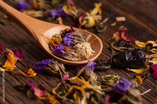 Healing tea made from dried flowers in a wooden spoon close-up. Dried flower petals close-up. Healing tea made from dried flowers. Dried tea petals from flowers close-up.