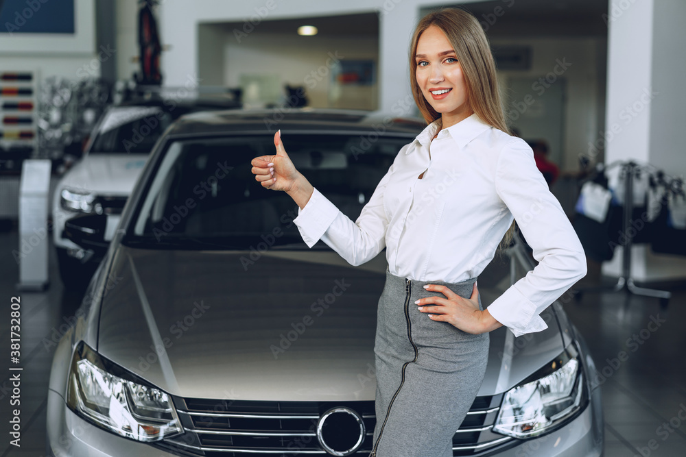 Happy beautiful young woman car dealer in showroom
