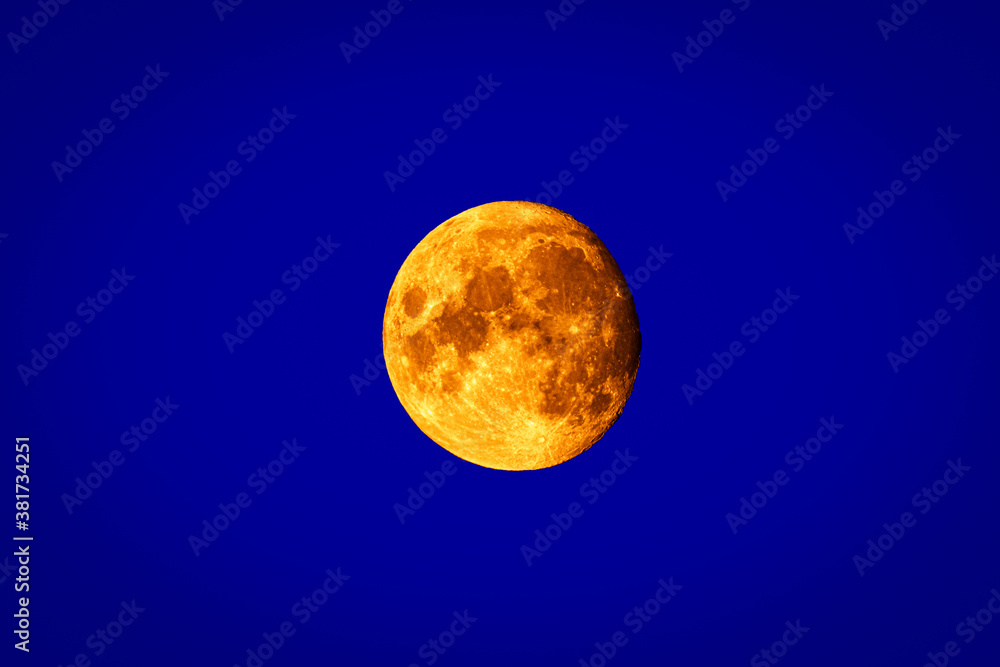 Fototapeta premium Full moon isolated on blue background. Close up Image.
