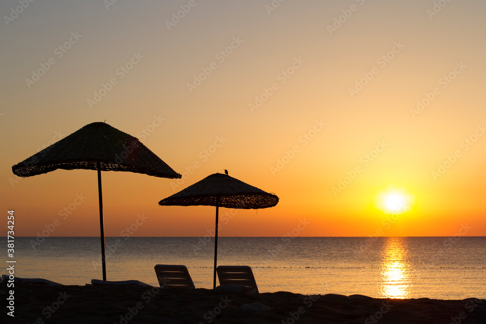 wicker umbrellas on the beach at sunset