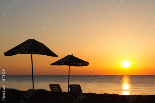 wicker umbrellas on the beach at sunset