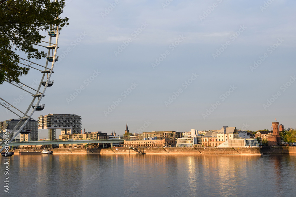 Photo of a river with a Ferris wheel and buildings in the morning sun