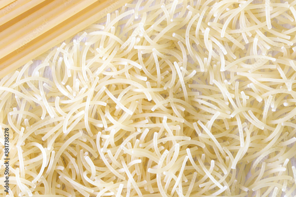 Uncooked italian pasta as background texture close up. Small layer of dry noodles. The food background is a pasta texture. Homemade noodles. Cooking. Background. Texture. View from above. Cooking. Uncooked italian pasta as background texture close up. Small layer of dry noodles. The food background is a pasta texture. Homemade noodles. Cooking. Background. Texture. View from above. Cooking.