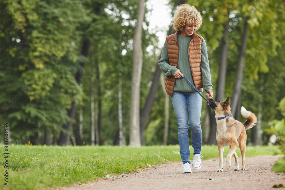 Obraz premium Young woman walking together with shepherd dog in the park outdoors
