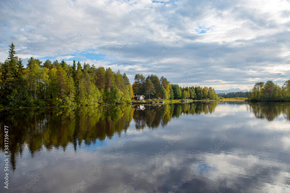 Beautiful landscape in Finland at the lake shore. Reflecting waters and cloudy sky. Calm scenery for poster and wallpaper use.
