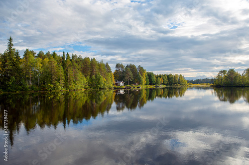 Beautiful landscape in Finland at the lake shore. Reflecting waters and cloudy sky. Calm scenery for poster and wallpaper use.