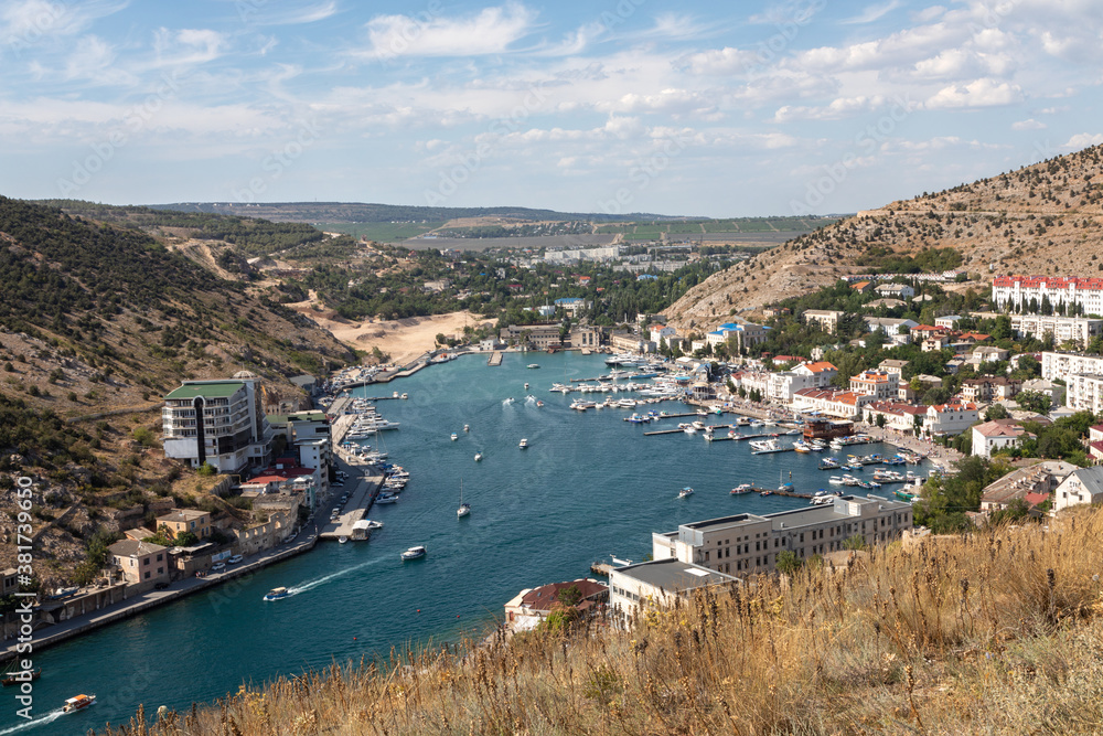 Picturesque panoramic view of Balaclava bay with yachts and green hills opens from the ruins of Genoese fortress Chembalo. Balaklava, Sevastopol, Crimea.