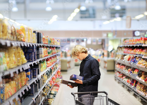 Man shopping in supermarket, reading product information 