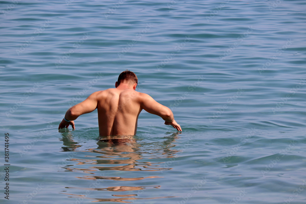 Man going to swim in a sea. Beach vacation and water leisure