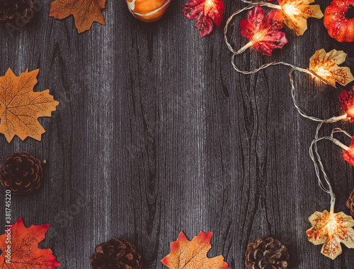 autumn leaves on wooden backgroundAutumn leaves, pine cones and a garland on a wooden background with a place for text in the middle, top view close-up.