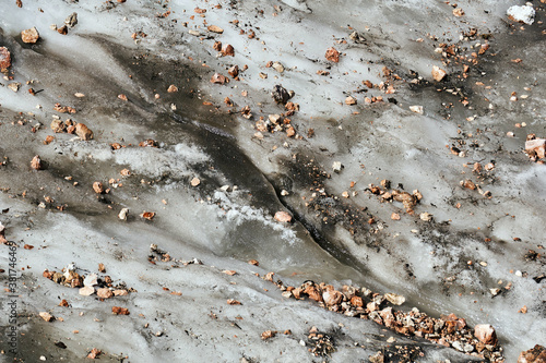 surface of a melting mountain glacier covered with stones and rubble