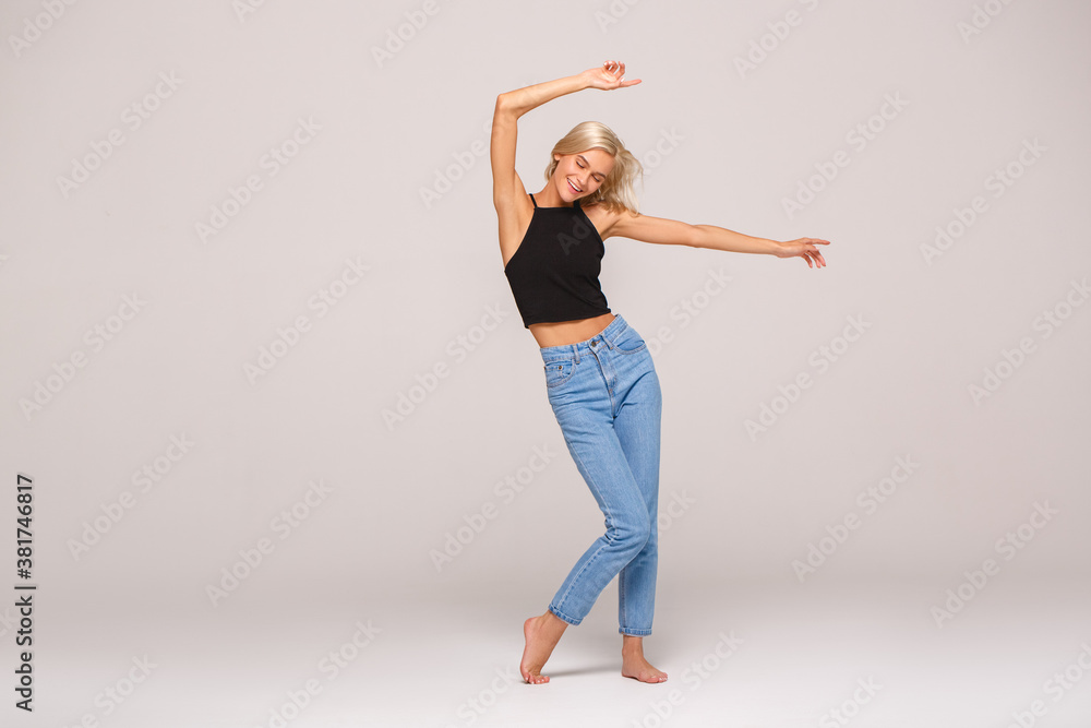 Young adult woman dancing on light grey background