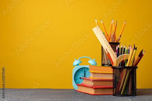 Office cup with pencils and stationery against yellow background photo