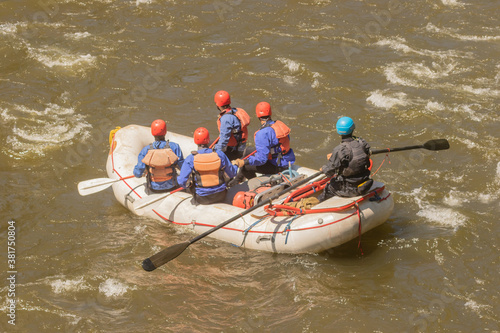 group of men whitewater rafting on a river 