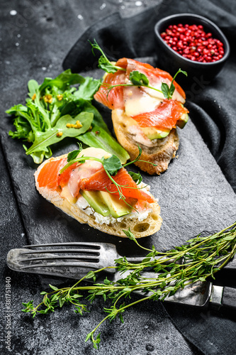 Toasts with avocado and smoked salmon.  Black background. Top view