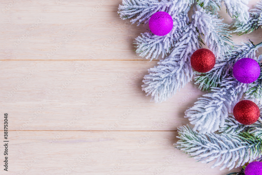 Frosty fir tree branches and decorative balls on wooden background with copy space