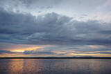 Dramatic cloudscape at sunset. Reflection of the sky in the water. Thunderclouds over the lake.